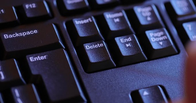 Hitting the Delete key on a keyboard, dramatic dim light