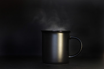 coffee in a black mug with boiling water on a black background