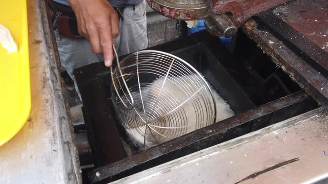 Close up of churros being fried in hot oil and stirred with large scoop