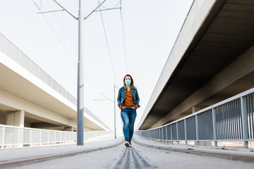 Young woman with a surgical mask in an empty tram station
