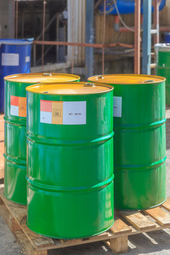 Three green barrels with label Poison on wooden pallets