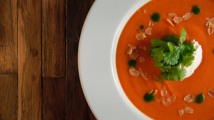 Delicious gazpacho in a white bowl on a rustic wooden table shot from above
