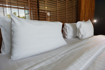 Beautiful white pillows, soft and luxurious on the bed, with bedroom lamp decoration