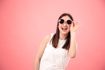 Portrait of a young woman with glasses on a pink background.