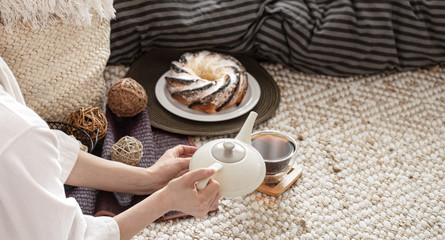 Hands of a young woman pour tea from a teapot.