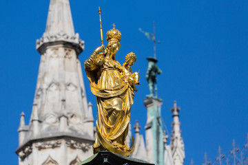 Fototapeta na wymiar Munich, Bavaria / Germany - Mar 18, 2020: Close up of Marienstatue at the Marienplatz (Mary's Square). A golden colored statue of the Holy Virgin Mary. Erected in 1638 by Duke Elector Maximilian I.