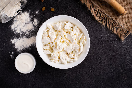 Fresh cottage cheese. Products for making cheesecakes on a black background. Healthy food. Top view. Copy space.