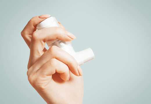 Female hand with a medical asthma inhaler, close-up.