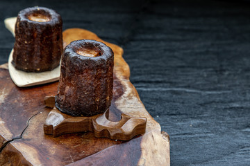 Cannelés (Canelés) de Bordeaux Recipe is a small pastry with rum and vanilla on a wooden plate.