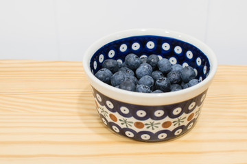 Bol con arandanos grandes en una cocina con fondo blanco
