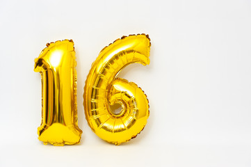 Inflatable numeral 16 sparkling metallic golden color isolated on white background. Close-up. Copy space. Horizontal shot.
