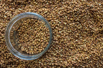 A close-up of buckwheat scattered on the surface with space for copying and a glass transparent jar