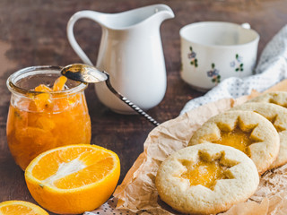 Fresh, fragrant handmade cookies, lying on a cutting board and jam of orange slices. Close-up, side view. Tasty and healthy eating concept