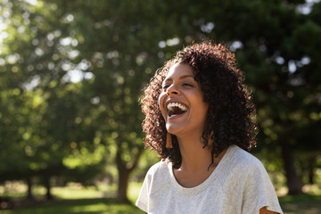 Laughing young woman enjoying a sunny day in the park - Powered by Adobe