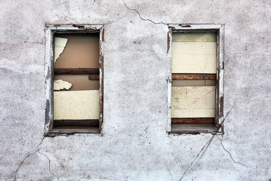 Boarded up windows and cracked peeled dirty walls of an abandoned old building