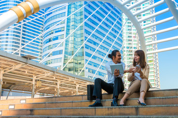 Businesspeople using tablet and mobile while sitting on the stai