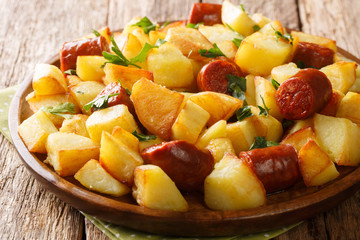Homemade food fried potatoes with sausages and herbs close-up in a plate. horizontal