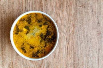 Bowl of soup on a wooden background. Soup of potatoes, spinach, carrots, meat. Copy space