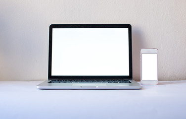 Laptop computer with blank screen and smartphone with mock up screen in office on the white background. Mock up screen in notebook. White office concept. Minimalism concept