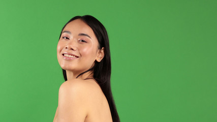 Women's beauty. Portrait of young smiling asian woman isolated on green background. Asian Caucasian Mixed Race Model Looking At Camera