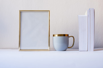 Gold frame mock-up. Blank frame with gray mug and succulent by the white wall. Mock up frame concept. Minimalism concept