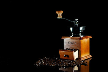 Coffee beans and vintage wooden coffee grinder on black background.