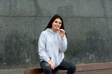 Attractive young woman with lollipop sitting on steps outdoors