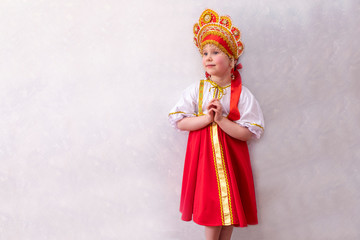 Child 5 years old girl dressed in national Russian clothes red sundress. And the traditional headdress is kokoshnik. Ethnic traditions