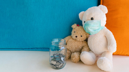 Teddy bear with surgical face mask look at coins in glass bottle money savings, worry about illness and insufficient money to pay medical expenses. Concept of health insurance, medicare and finance.