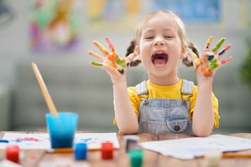 Happy kid is painting at home.