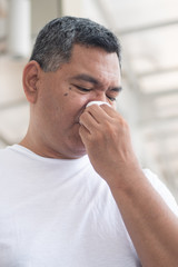 Fototapeta premium allergic sick old man wiping his runny nose and touching his face; concept of man with coronavirus covid-19 infection disease, allergy, lung inflammation, pneumonia, influenza, flu, cold, sickness