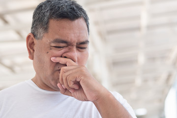 allergic sick old man wiping his runny nose and touching his face; concept of man with coronavirus covid-19 infection disease, allergy, lung inflammation, pneumonia, influenza, flu, cold, sickness