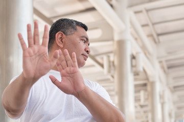 old man showing rejecting, stopping hand gesture; concept of forbidding, no way, rejection, negative answer, halt, stop, warning, social distancing; southeast asian senior old man model