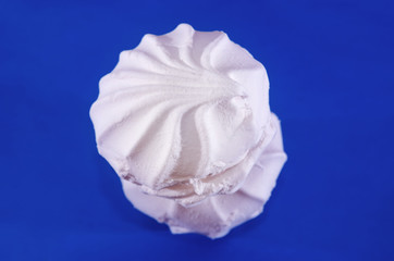 two white marshmallows on a blue background. Close-up.