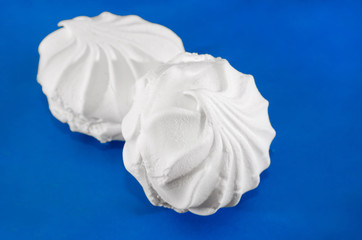 two white marshmallows on a blue background. Close-up.