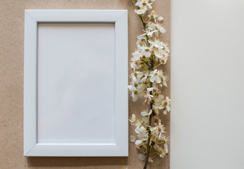 White blank frame on beige background with flower. Minimalistism background. Mock up frame. Summer or travel concept. Copy space