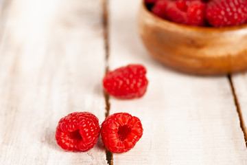 Ripe red raspberry on rustic wooden background. Healthy dessert, summer mood. Macro, close up, front view, copy space