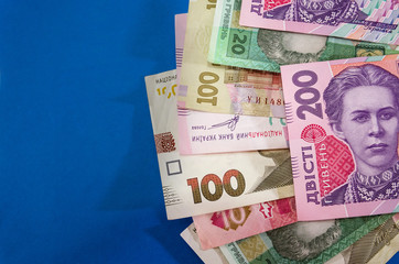 different hryvnias on a blue background. Copy space.