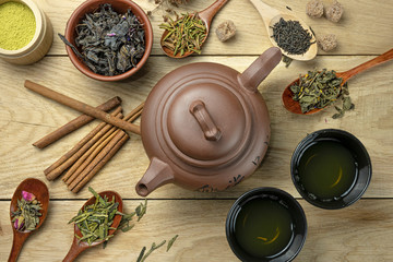 teapot with different types of tea and accessories stands on wooden table