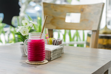 Fresh dragon fruit juice is served in a unique jar and bamboo straw.