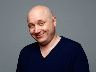 Fototapeta premium Portrait of a bald cheerful man on a gray background