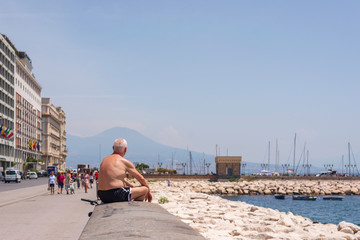 old man resting in the sun on the promenade of the mediterranean sea