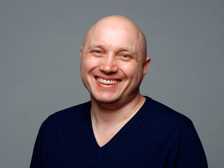 Portrait of a bald cheerful man on a gray background