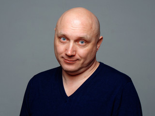 Portrait of a bald cheerful man on a gray background