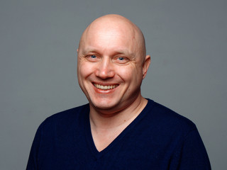 Portrait of a bald cheerful man on a gray background