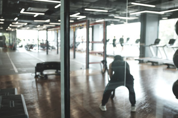 Blur abstract background of exercise equipments in in modern fitness gym. Blurry people work out in...