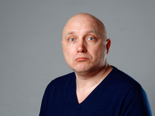 Portrait of a bald cheerful man on a gray background