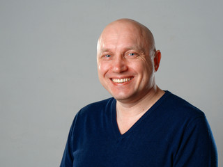 Portrait of a bald cheerful man on a gray background