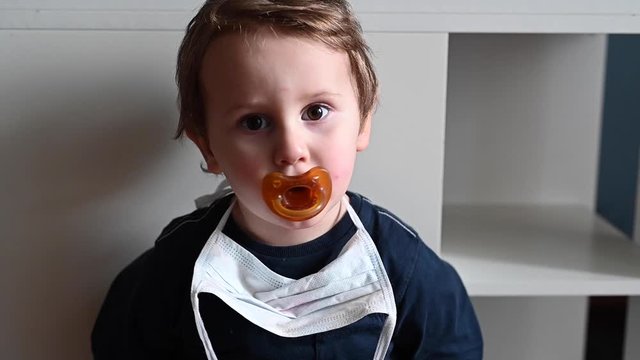Slow motion of a baby kid with pacifier and surgical mask
