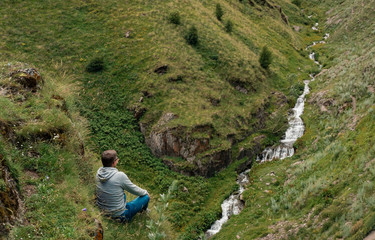 Close up Man Traveler sitting on cliff with mountain river view. mountains success and fun euphoria...